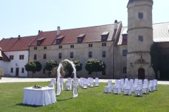Detail svatebního oblouku s výzdobou na míru na pozadí renesanční architektury zámku Libouchec.