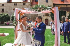 Výměna prstýnků během obřadu na míru v zahradě u Teplic.