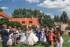 Šťastný pár kráčející špalírem po obřadu v zahradě zámku Libouchec.