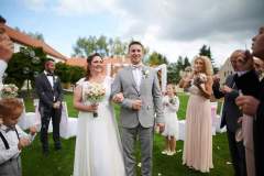 Šťastný pár kráčející špalírem po obřadu v zahradě zámku Libouchec.